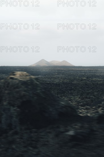 Serene Lanzarote landscape featuring vast volcanic plains and distant, hazy mountains under a muted