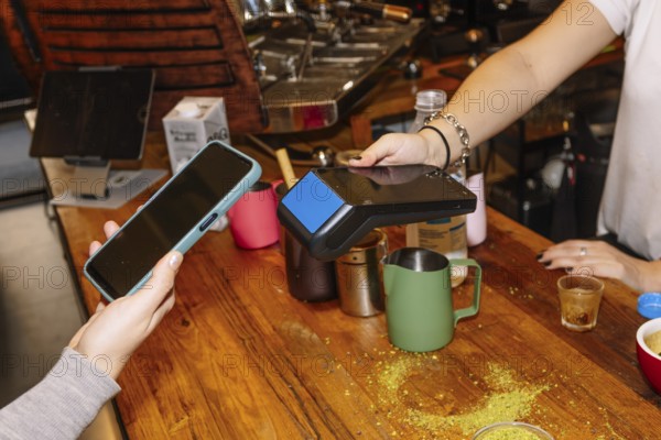 A customer uses a smartphone for contactless payment at a trendy specialty coffee shop, showcasing