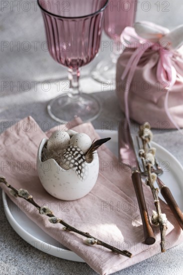 Soft pastel pink easter table setting decor. A white ceramic egg holder, adorned with subtle