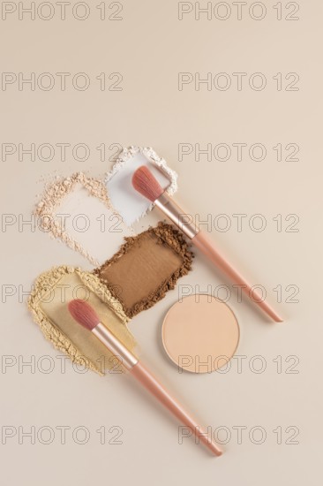 Top view of compact and loose powders with makeup brushes on a neutral background. This shot