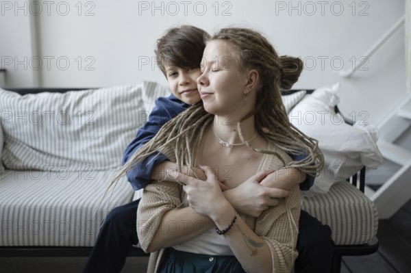A tender moment between a mother and her son as they hug affectionately on a striped sofa The