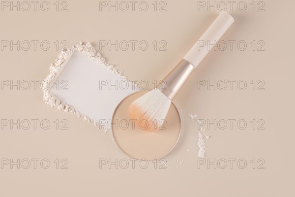Top view of a makeup setting displaying a compact with loose face powder beside it, scattered
