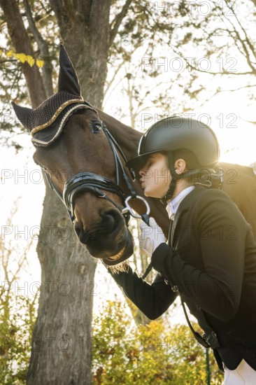 From below teenage girl, dressed in classical dressage attire, is affectionately interacting with a