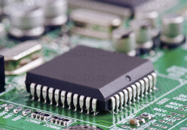 A detailed macro shot of a microchip securely mounted on a green printed circuit board,