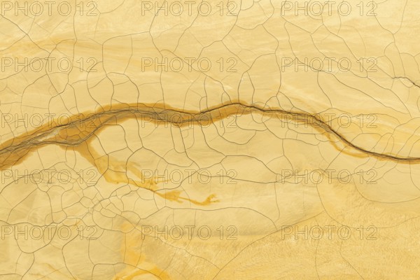 Intricate texture of golden mud with a distinct crack pattern that intertwines elegantly across the