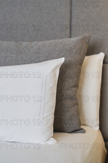A close-up of a hotel room showcasing neatly arranged pillows on a textured headboard, highlighting