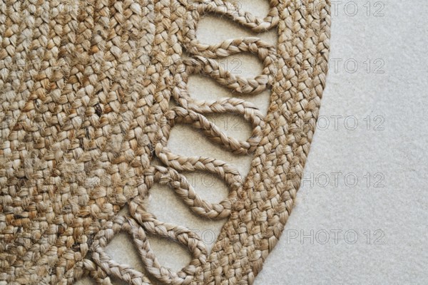 Detailed close-up of a braided jute rug showcasing its intricate woven design. The natural fibers