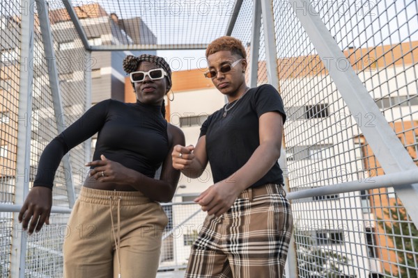 A vibrant LGBT multiethnic couple poses joyfully in a modern urban setting, exuding confidence and