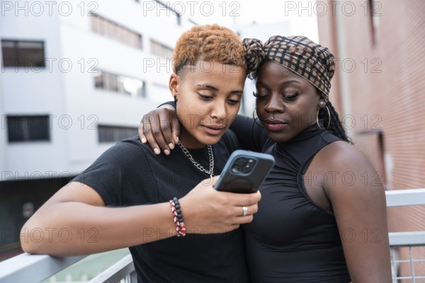 A loving multiethnic couple stands close, sharing a moment while looking at a smartphone. They