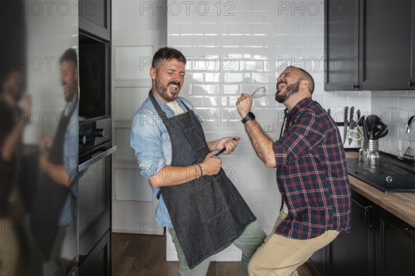 A cheerful gay couple enjoys a playful moment in their modern kitchen, passionately dancing and