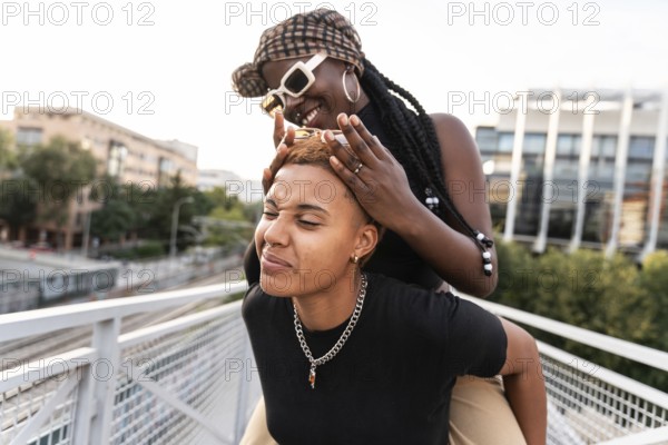 A joyful LGBT multiethnic couple shares playful moments outside. They enjoy each other's presence