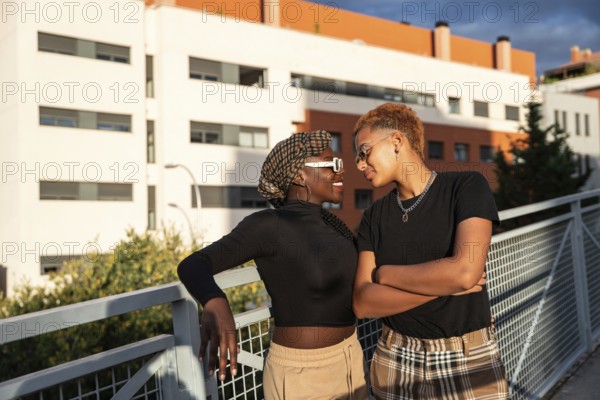 A loving LGBT multiethnic couple shares a tender moment on a sunny day, standing by a rail with