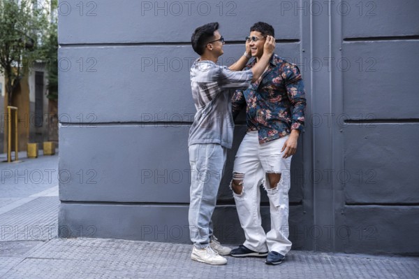 A latin gay couple enjoys a playful moment on an urban street, showing affection. They wear casual
