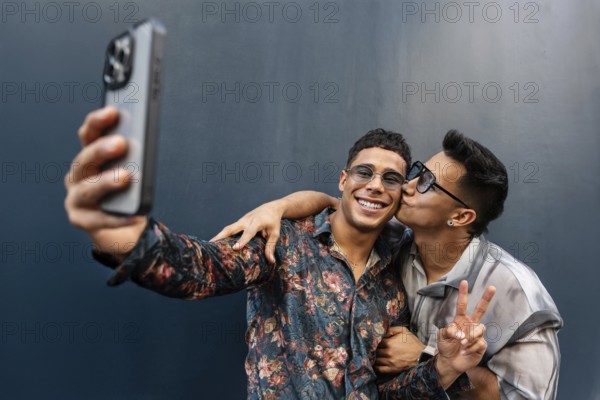 A joyful latin gay couple takes a selfie, capturing a moment of affection and happiness. One person