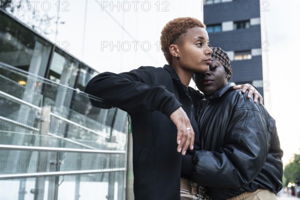 A loving LGBT multiethnic couple embraces outdoors in an urban environment. The moment captures