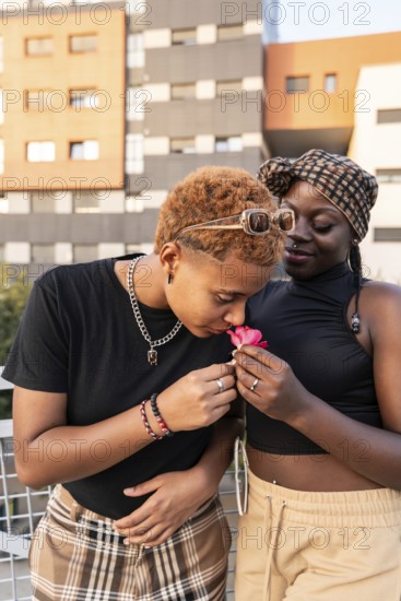 A joyful LGBT multiethnic couple shares a tender moment outdoors. One person gently sniffs a