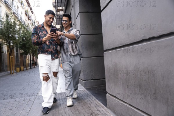 A joyful latin gay couple exploring Madrid, sharing moments and looking at a smartphone while