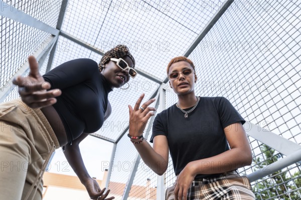 A dynamic LGBT multiethnic couple poses confidently in an urban setting. Both showcase unique