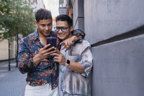 A joyful latin gay couple stands close together on a sunny street in Madrid, sharing a moment as