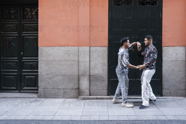 A joyful latin gay couple shares a moment of affection on a lively street in Madrid. Their
