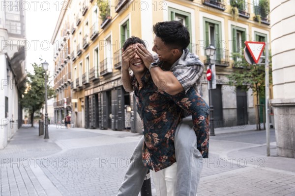 A happy latin gay couple enjoys a playful moment in the vibrant streets of Madrid. They are