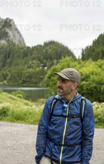 A man in outdoor gear enjoys the serene landscape at Lac de Taney, Switzerland Surrounded by lush
