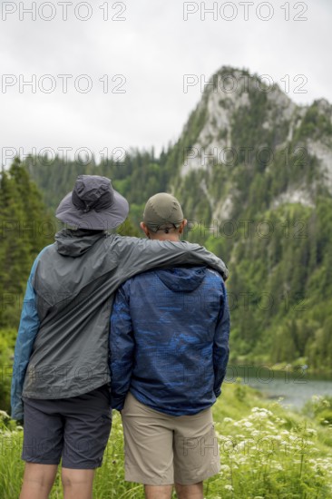 Two people embrace while admiring the picturesque mountain landscape of Lac de Taney, Switzerland