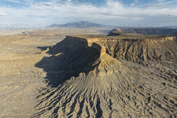 Dramatic aerial view of Caineville Mesa in Utah, USA, showcasing rugged terrain, layered rock