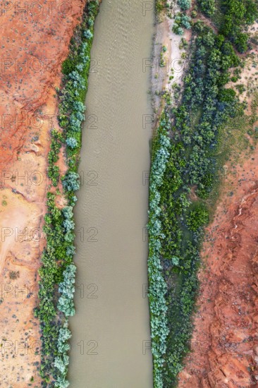 A striking aerial shot of the Rio San Juan winding through vibrant red rock landscapes, contrasted