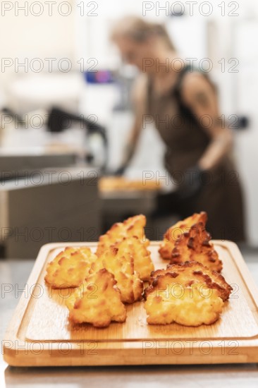 Freshly baked Italian pastries sit on a wooden board in a warm bakery A baker is seen working in