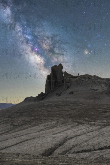 Unrecognizable person silhouette stands on a rugged Utah desert terrain under a vivid Milky Way.