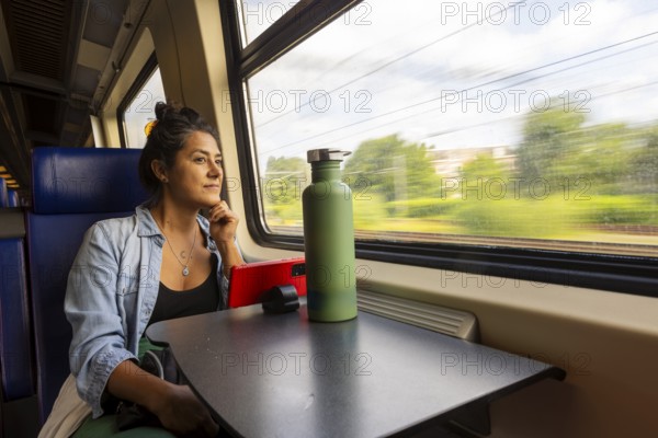 A thoughtful passenger gazes out a train window, absorbing the scenic landscape Sunlight filters