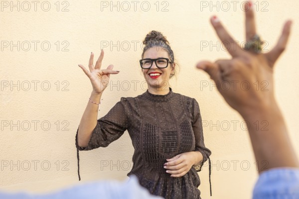 A cheerful instructor in glasses teaches sign language, engaging with a participant in an outdoor