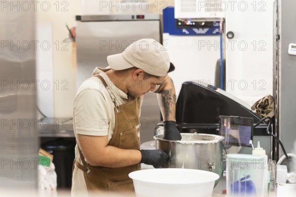 A dedicated baker in a traditional Italian bakery mixes dough in a stainless steel bowl, showcasing