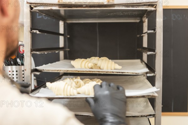 A baker places raw croissants onto a baking rack in an Italian bakery The scene captures the