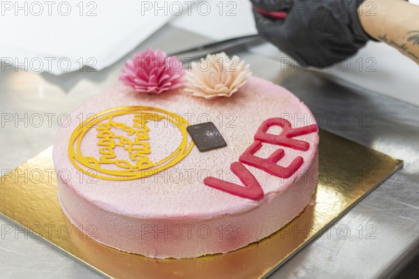 A beautifully crafted Italian birthday cake featuring pink floral decorations and a happy birthday