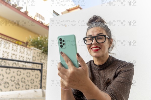 A woman is sitting outside, actively participating in an online sign language class using her