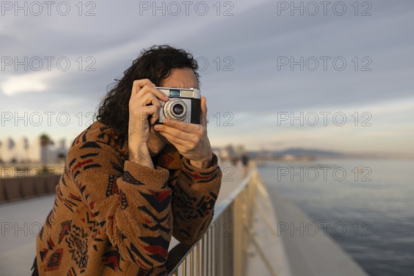 Casual moment of a young man enjoying photography by the scenic waterfront He is dressed in a cozy