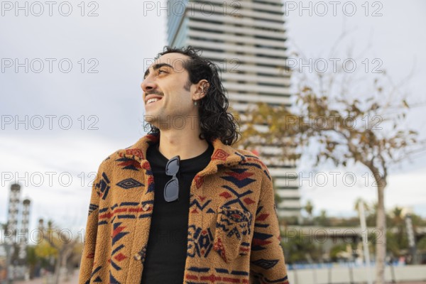A stylish man with a patterned coat and sunglasses smiles confidently in an urban setting A modern