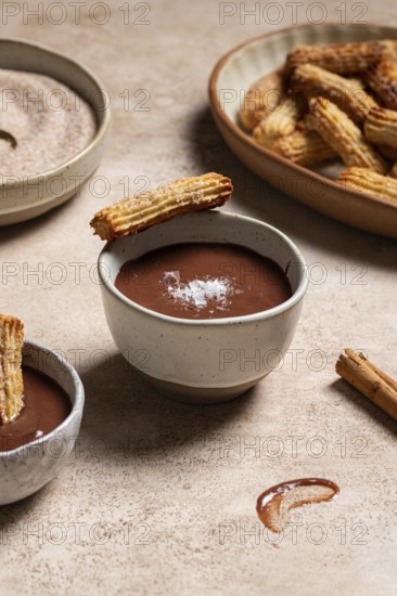 Homemade churros dipped in rich chocolate sauce, sprinkled with sugar and cinnamon, presented on a