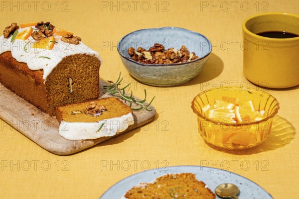 A moist carrot cake loaf topped with cream cheese frosting, garnished with walnuts and rosemary