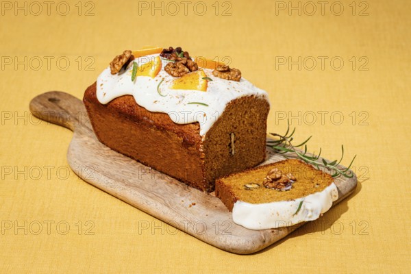 A freshly baked carrot cake loaf topped with cream cheese frosting, garnished with walnuts and
