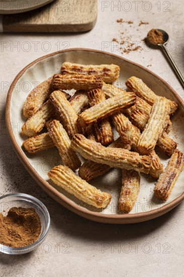 Homemade churros dusted with sugar and cinnamon, served on a ceramic plate alongside chocolate and
