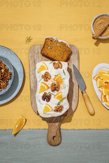 A delicious carrot cake loaf topped with creamy cream cheese frosting, garnished with orange