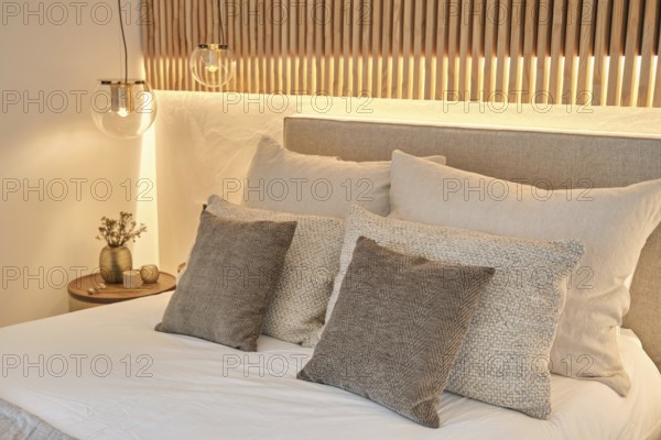 Modern bedroom featuring textured pillows, soft bedding, and ambient lighting with a wooden
