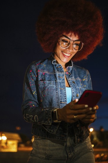 African descendent woman with a vibrant afro hairstyle, wearing glasses, joyfully engaging with her