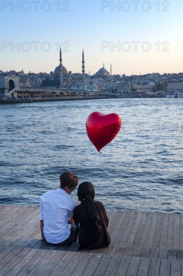 Istanbul, Turkey. 20th October 2019 A romantic couple sit beside the Golden Horn with a red heart
