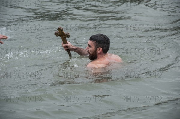 Istanbul, Turkey, January 6th 2017 A man holds a wooden cross after retrieving it from the Golden