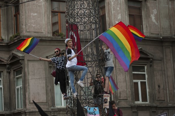 Istanbul, Turkey. August 21st, 2016 Rainbow flag waiving protestors climb a statue near Istiklal