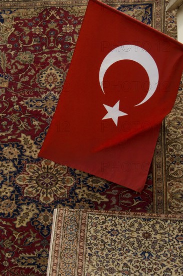 Istanbul, Turkey, February 23rd 2018. A Turkish flag and antique carpet for sale in a shop in the